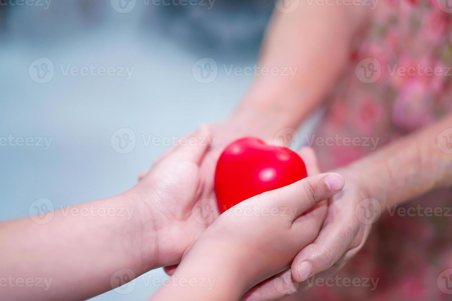 kind geeft rood hart aan senior grootmoeder. foto