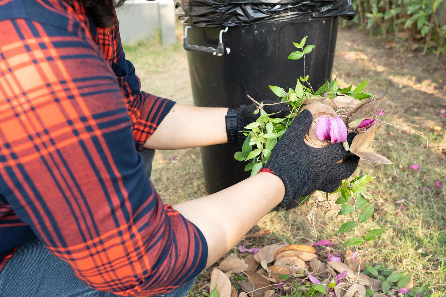 aziatische vrouw maakt schoon en verzamelt vuilnisbak droge bladeren vuilnis foto