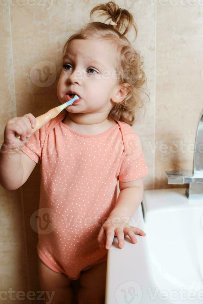 schattig en grappig baby meisje poetsen haar tanden in de ochtend- in de bad foto