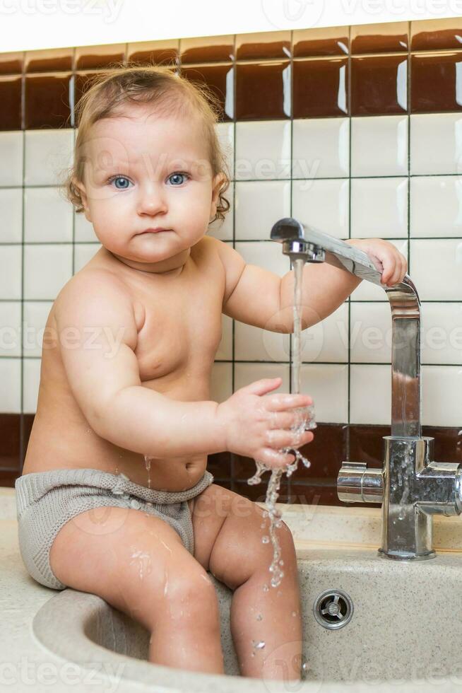 schattig baby spelen in de keuken wastafel foto