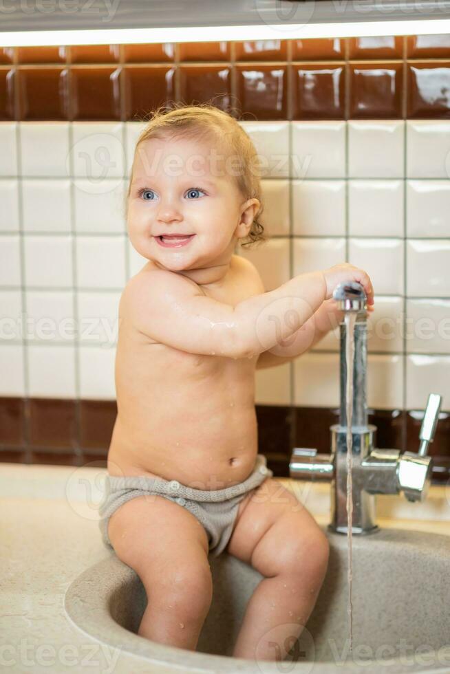 schattig baby spelen in de keuken wastafel foto