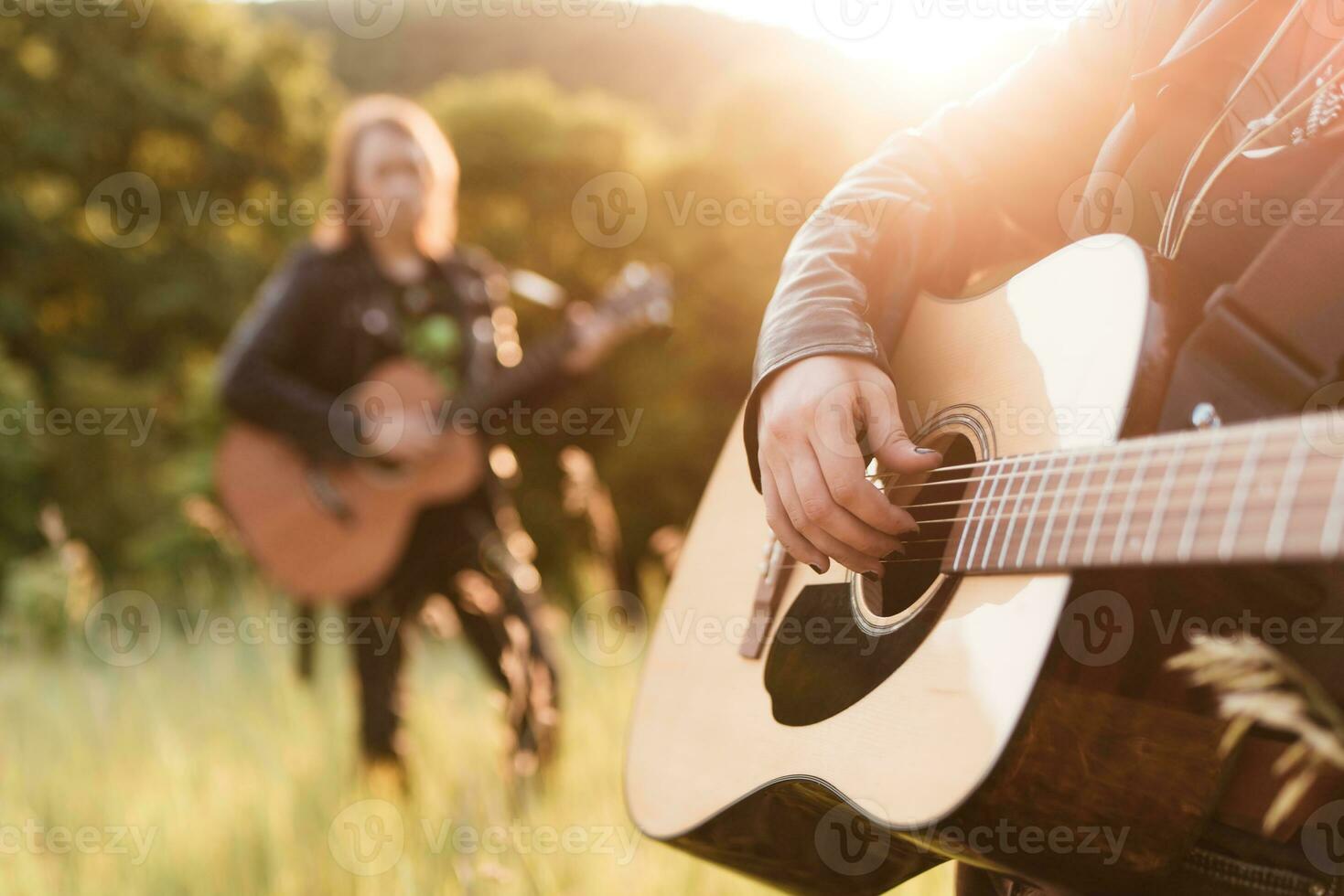 vrouw en Mens spelen akoestisch gitaar in natuur Bij zonsondergang foto