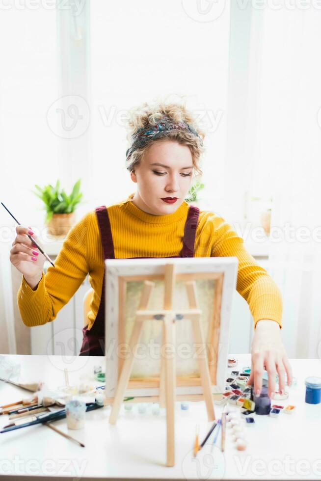 portret van een artiest meisje wie creëert een schilderij Bij huis foto