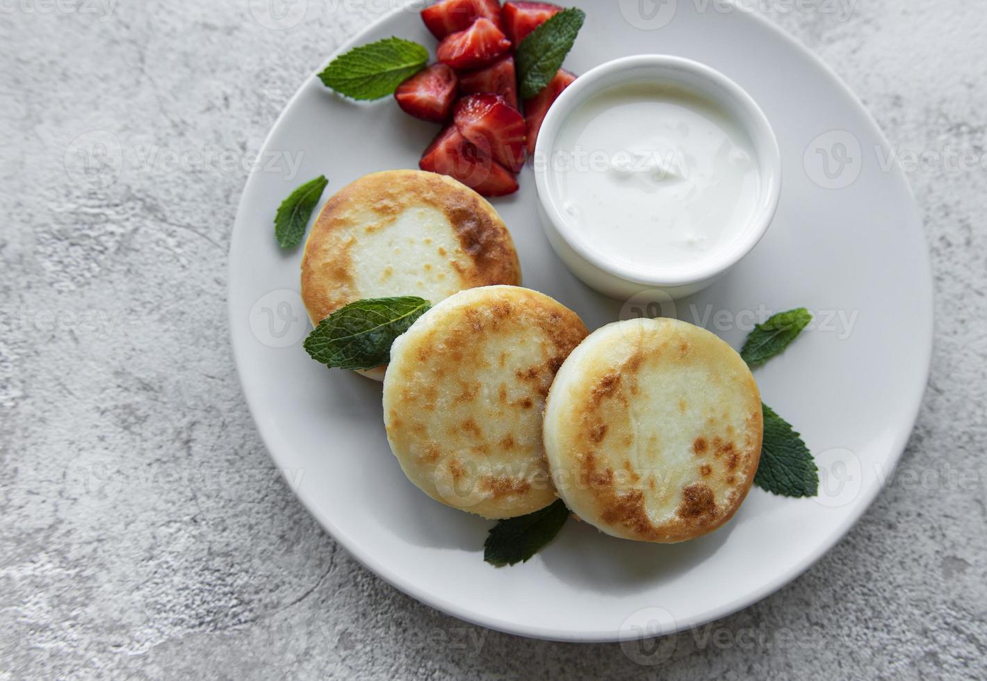 kwarkpannenkoekjes op keramische plaat met verse aardbeien. foto