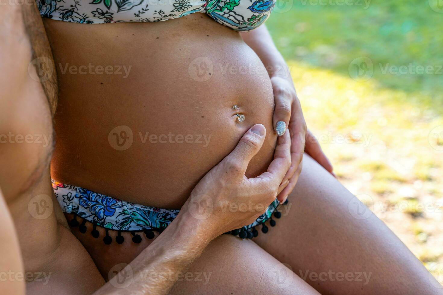 buik detailopname van een zwanger vrouw gestreeld door handen foto