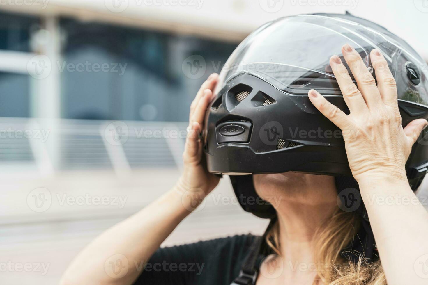 portret van midden- oud blond vrouw fietser zetten zwart helm Aan hoofd foto