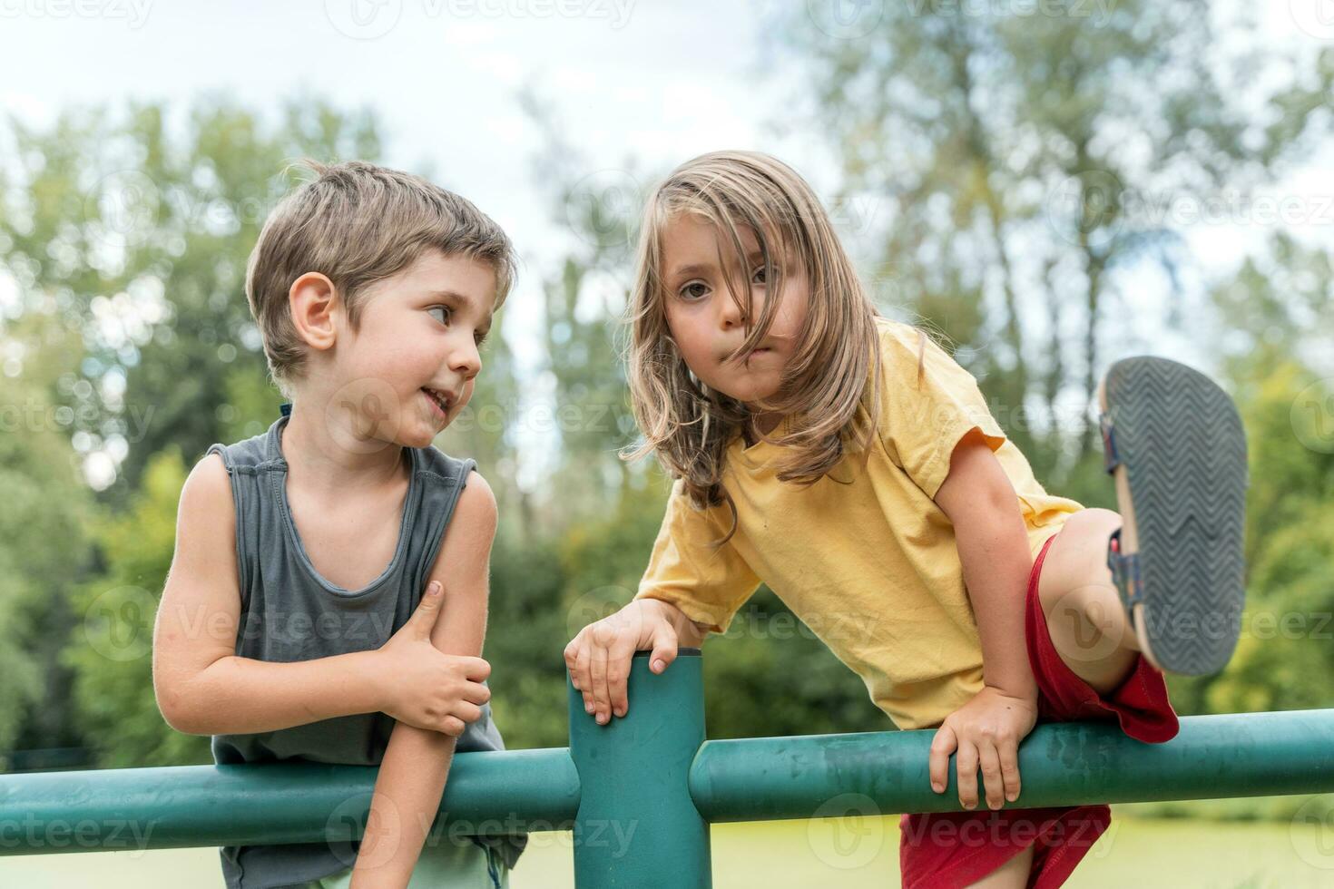 Tweelingen jongens en meisjes hebben pret beklimming metaal pijpen naar Speel foto