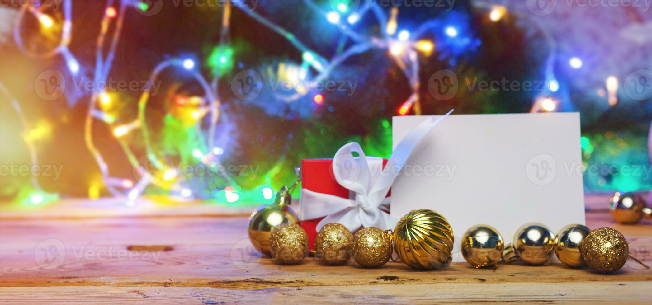 Kerstmis boom decoraties en geschenk doos met een blanco kaart Aan een houten tafel. Kerstmis speelgoed met blanco papier over- Kerstmis boom en lichten bokeh. vakantie decoratie. Kerstmis achtergrond foto