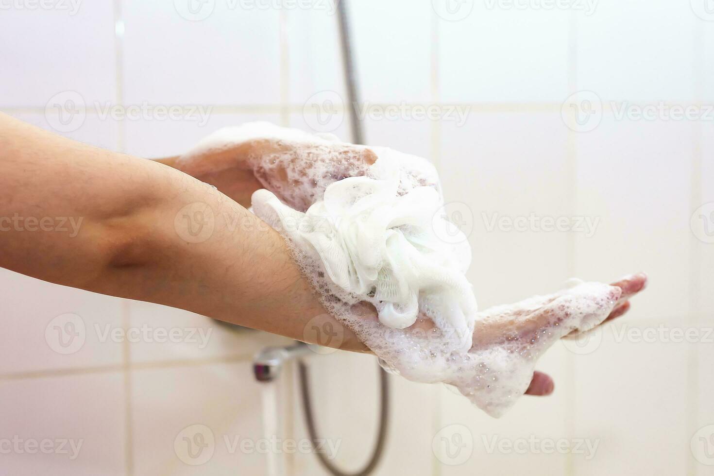 vrouw het wassen handen met een spons in de badkamer. vrouw het wassen armen met een schuimend spons in de bad. lichaam zorg en schoon concept foto