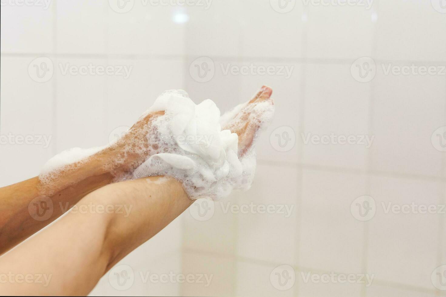 vrouw het wassen handen met een spons in de badkamer. vrouw het wassen armen met een schuimend spons in de bad. lichaam zorg en schoon concept foto