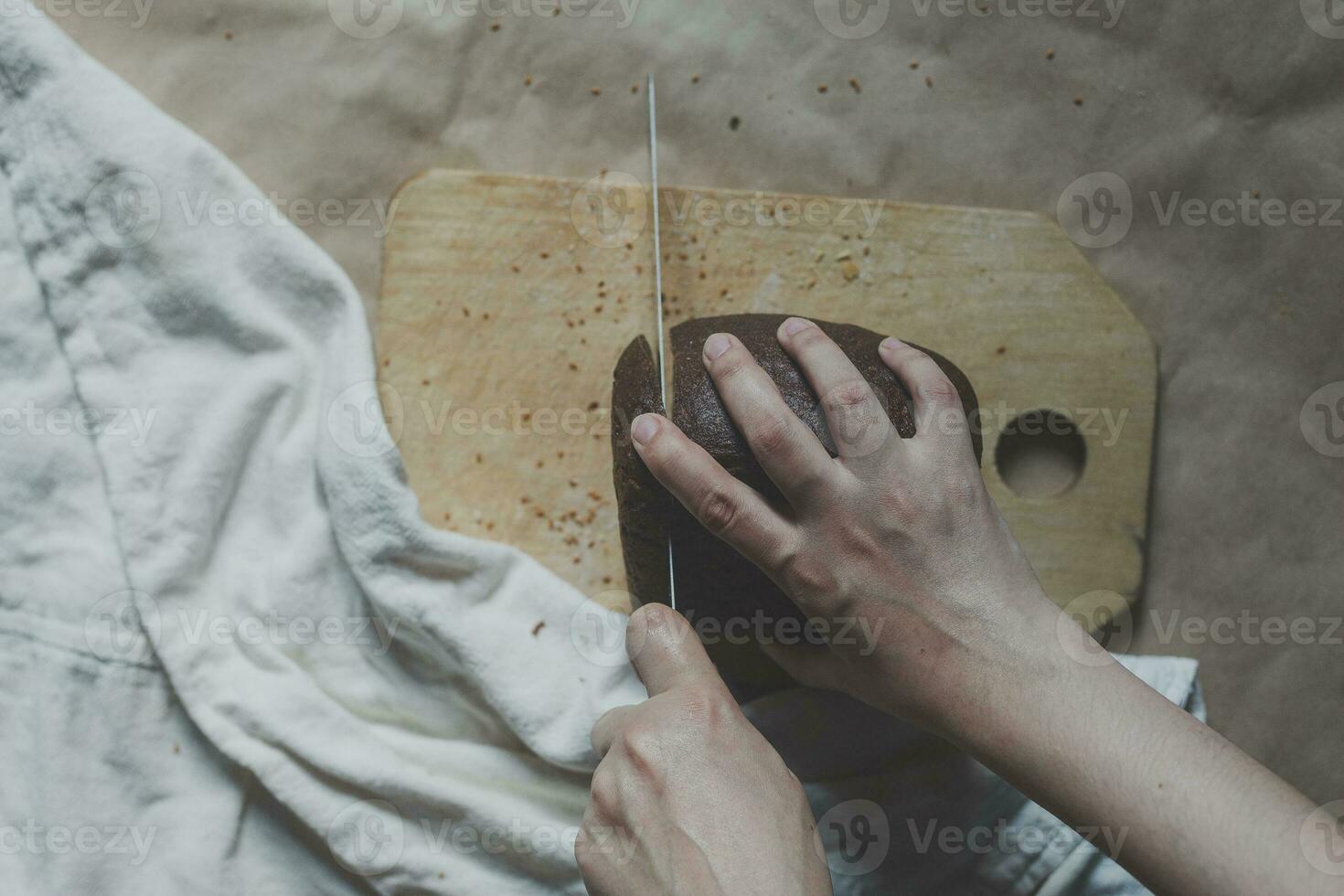 huisvrouw snijdend een brood. vrouw besnoeiing brood Aan snijdend bord. visie van bovenstaande. top visie van brood foto