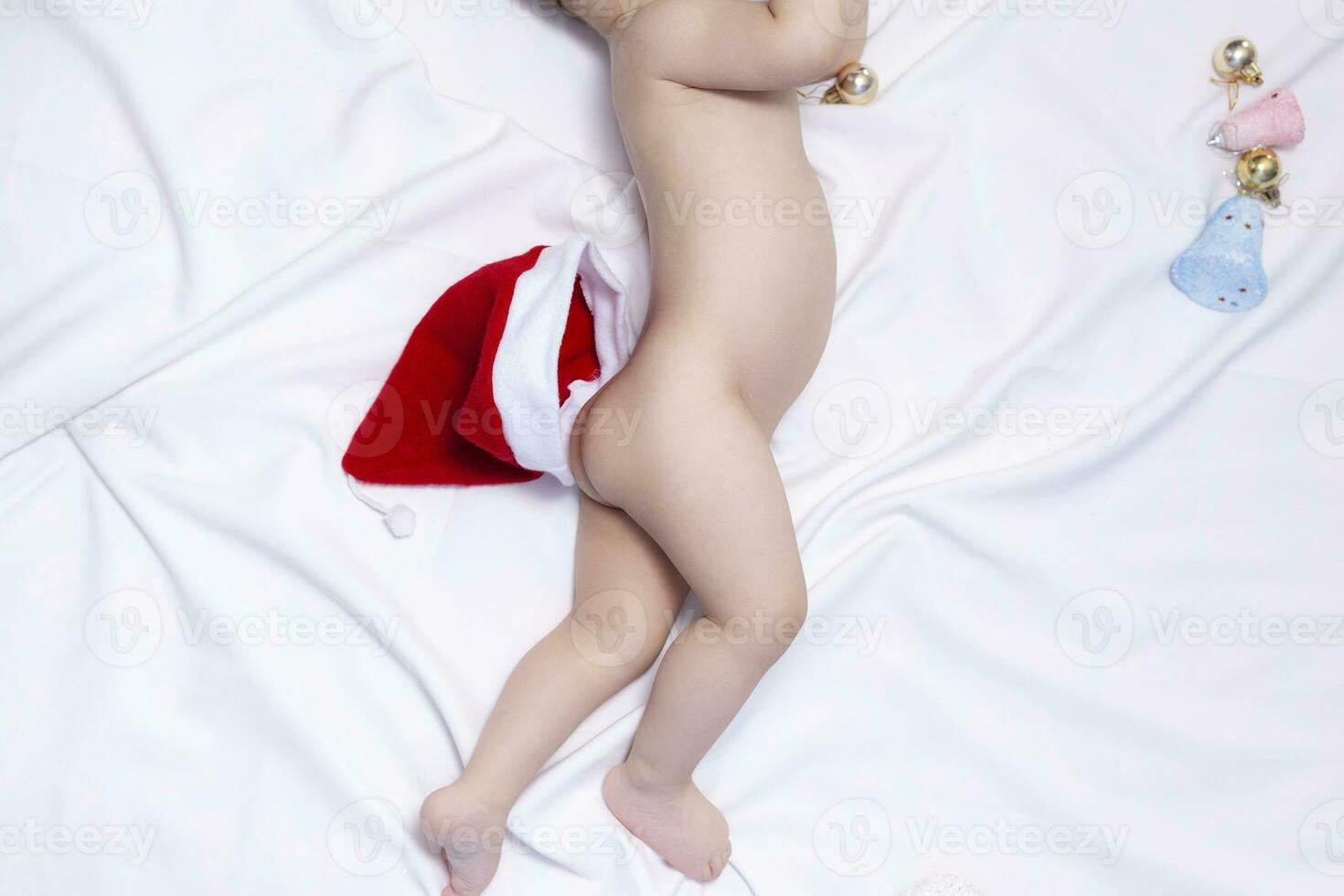 9 maanden baby jongen met de kerstman claus hoed Aan de kont. Kerstmis ochtend. weinig kind spelen. foto