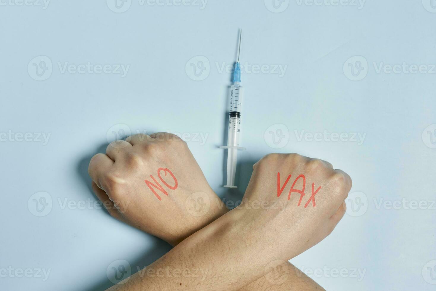 antivaxxer kruispunt handen in de buurt de injectiespuit met covid-19 vaccin foto