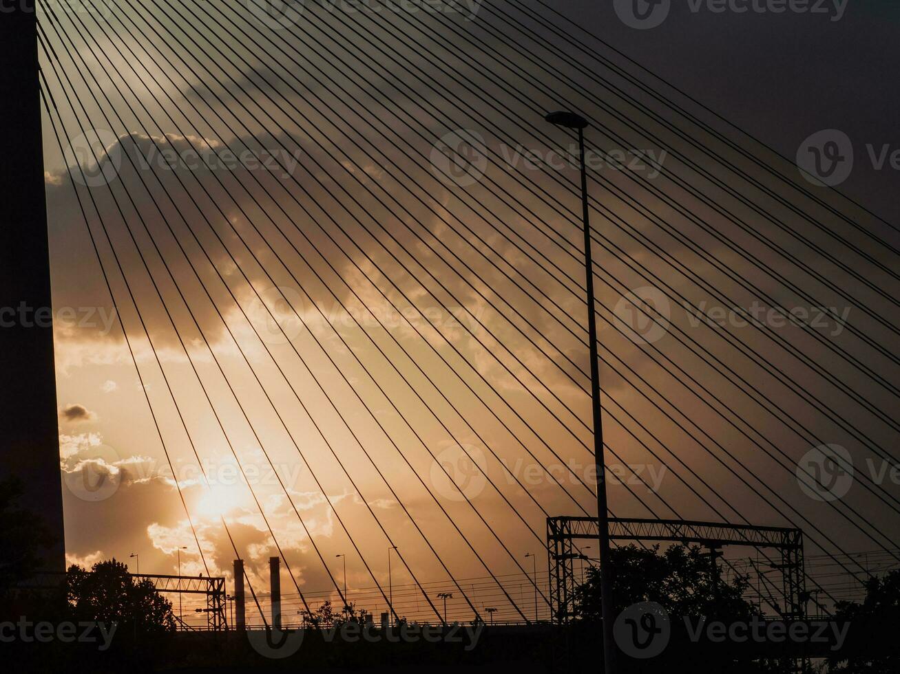 schemer gezien door de suspensie kabels van de brug - industrieel schoorstenen in de achtergrond foto