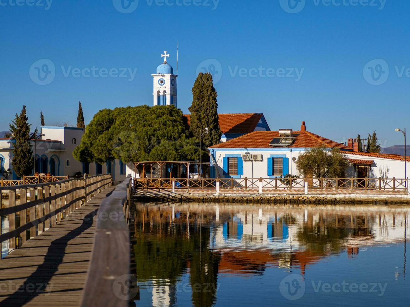 klein Grieks orthodox kerk Aan een klein meer eiland met een versmallen houten brug leidend naar het foto