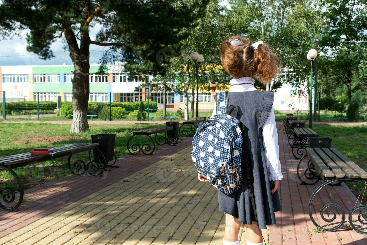 leerling met rugzak en in een school- uniform in school- werf terug naar de kader. terug naar school, september 1. een gelukkig leerling. primair opleiding, elementair klas. weg naar leven, naar kennis foto