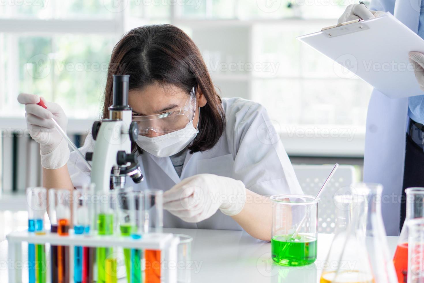 Aziatische wetenschapper die experiment doet met assistent in lab foto