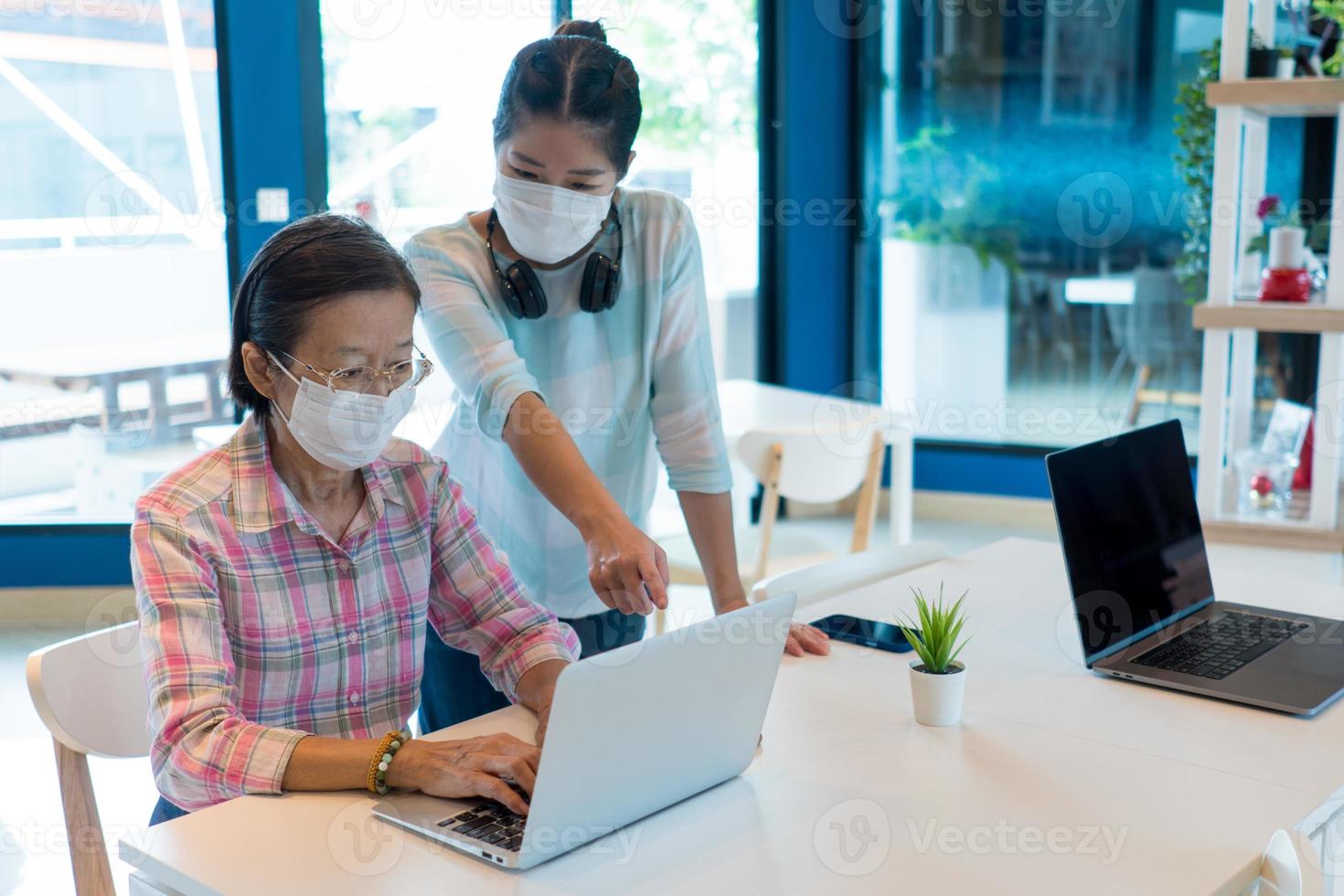 dochter draagt masker leer moeder computer te gebruiken tijdens pandemie foto