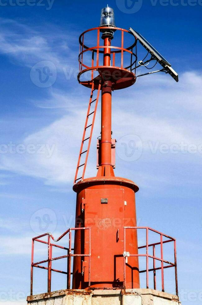 een rood vuurtoren met een zonne- paneel Aan top foto