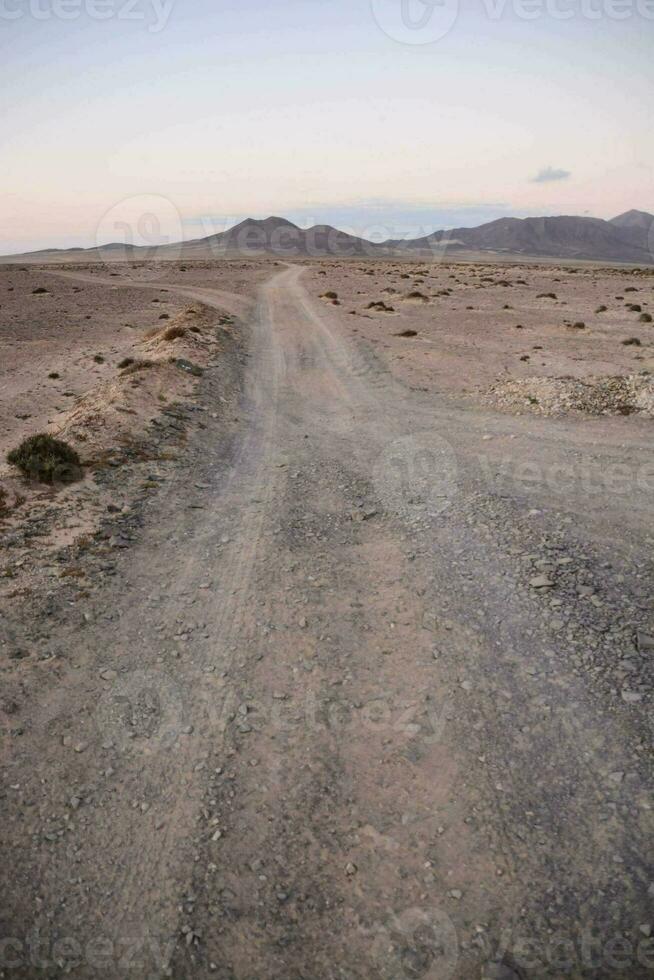 een aarde weg in de woestijn met bergen in de achtergrond foto