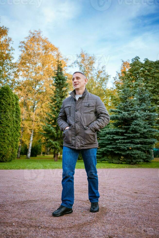 een Mens in een herfst jasje in de park staat Aan de pad foto