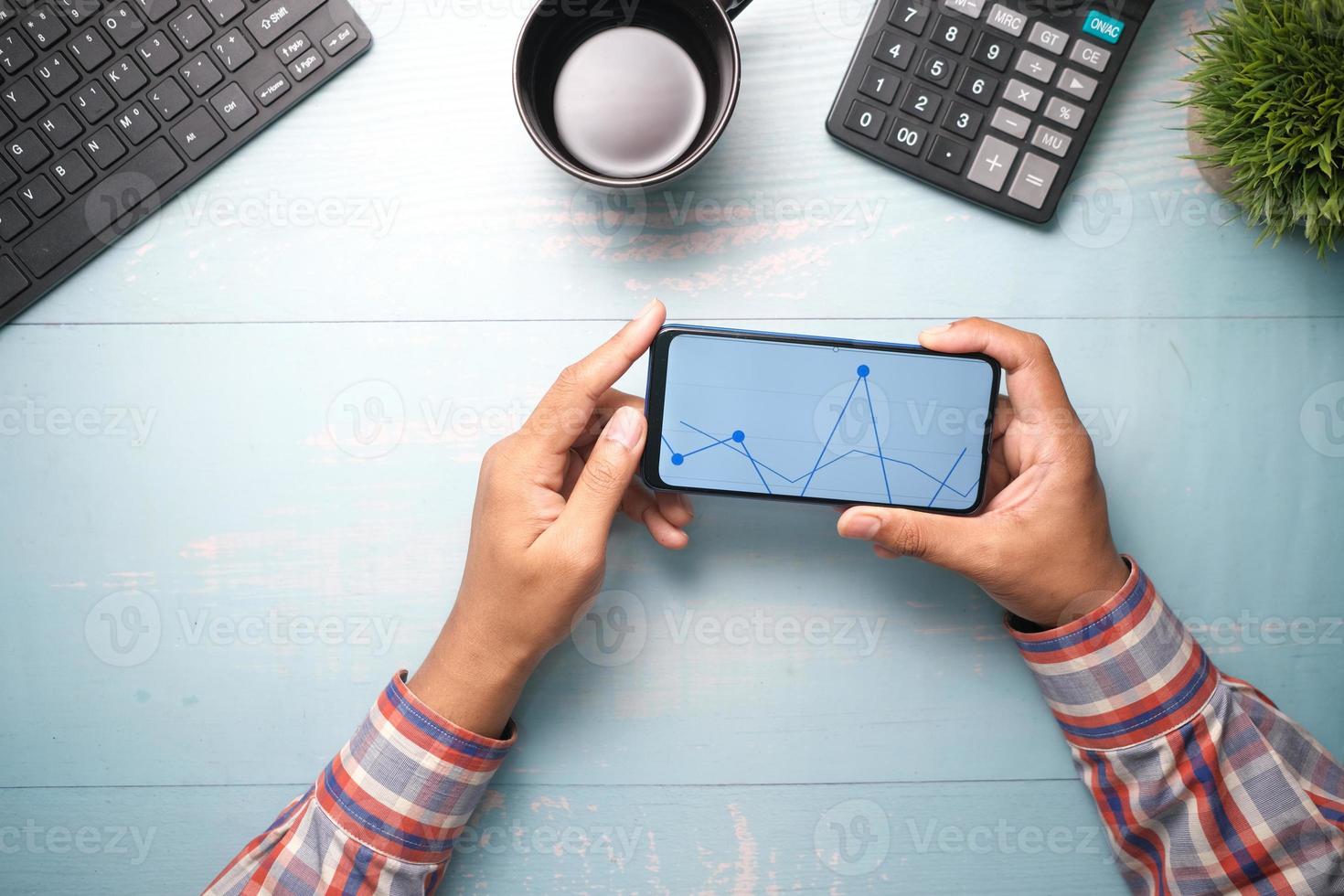 jonge man analyseert aandelengrafiek op smartphone foto
