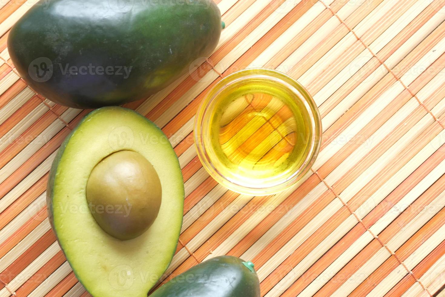 bovenaanzicht van olie en plakje avocado op houten tafel foto