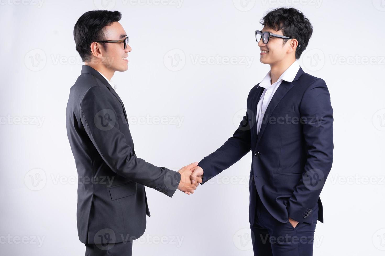 twee Aziatische zakenlieden die handen schudden op een witte achtergrond foto