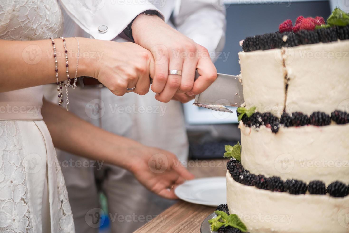 bruid en bruidegom snijden zoete cake op banket in restaurant foto