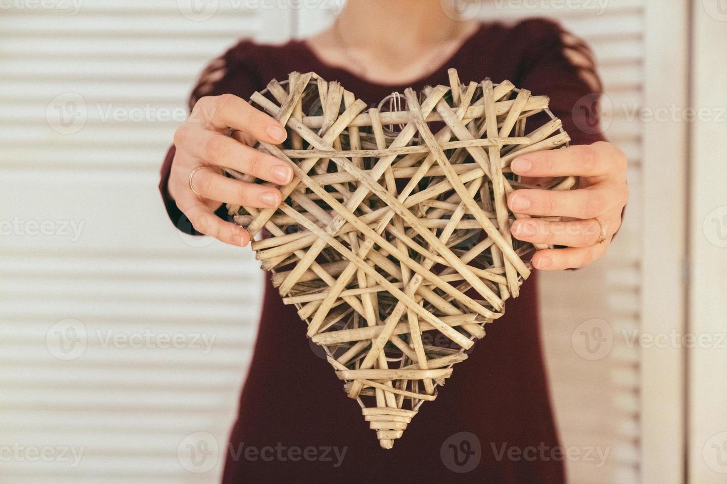 decoratief rieten hart in de handen van een vrouw foto