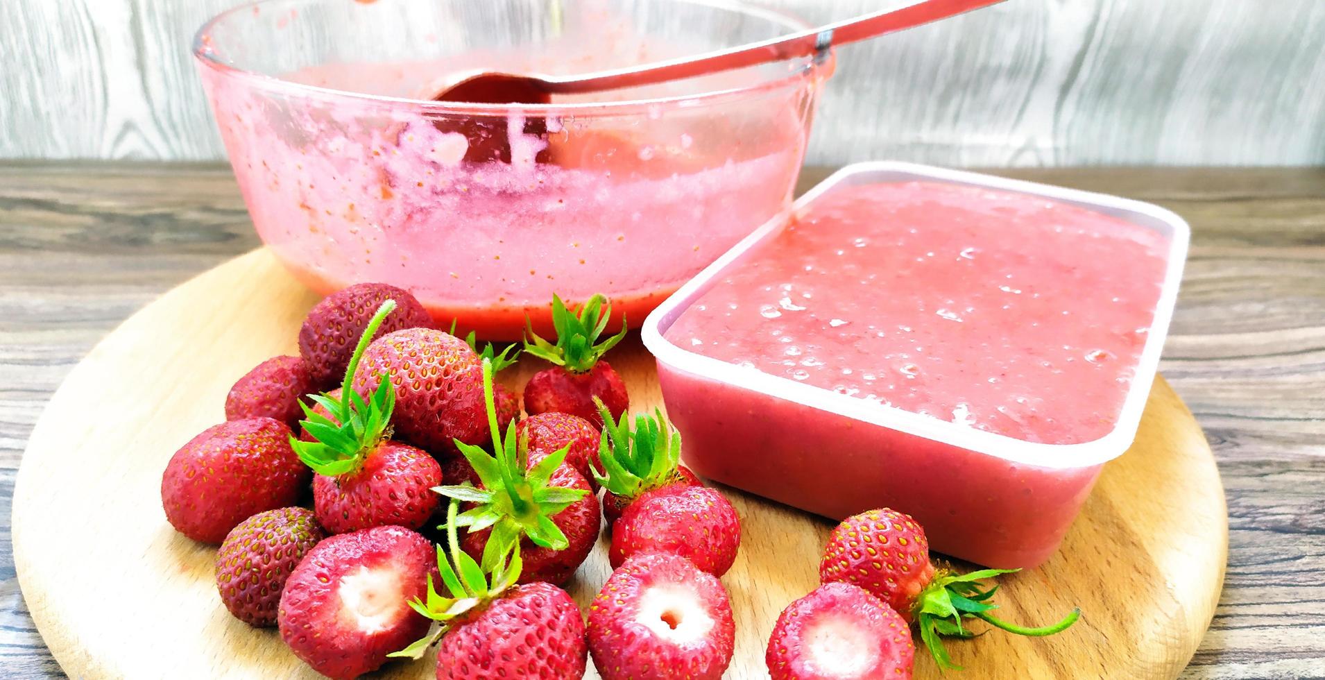 hele aardbeien liggen op een snijplank. glazen beker met fruit foto