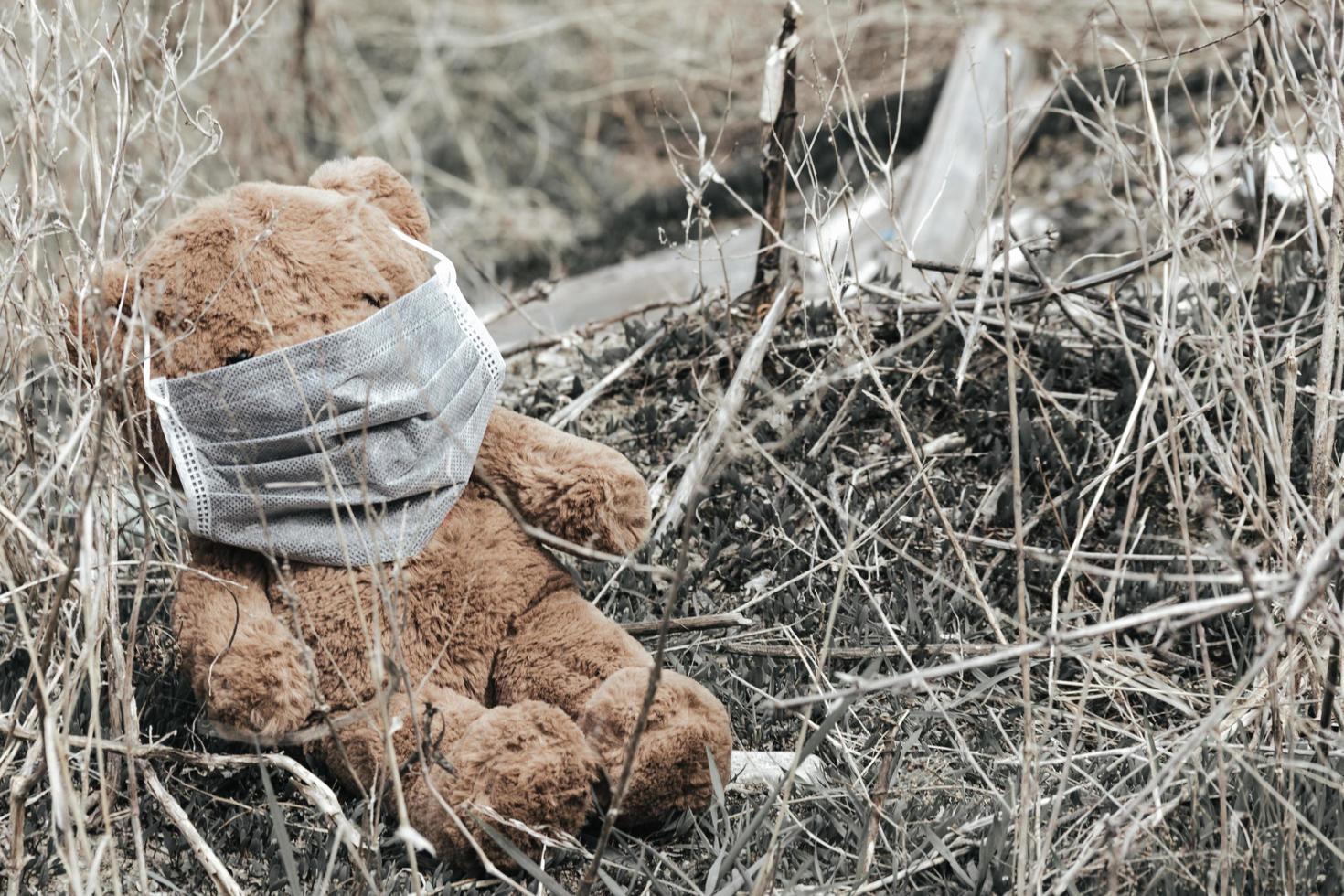 teddybeer met medisch masker zit in vuilnis foto