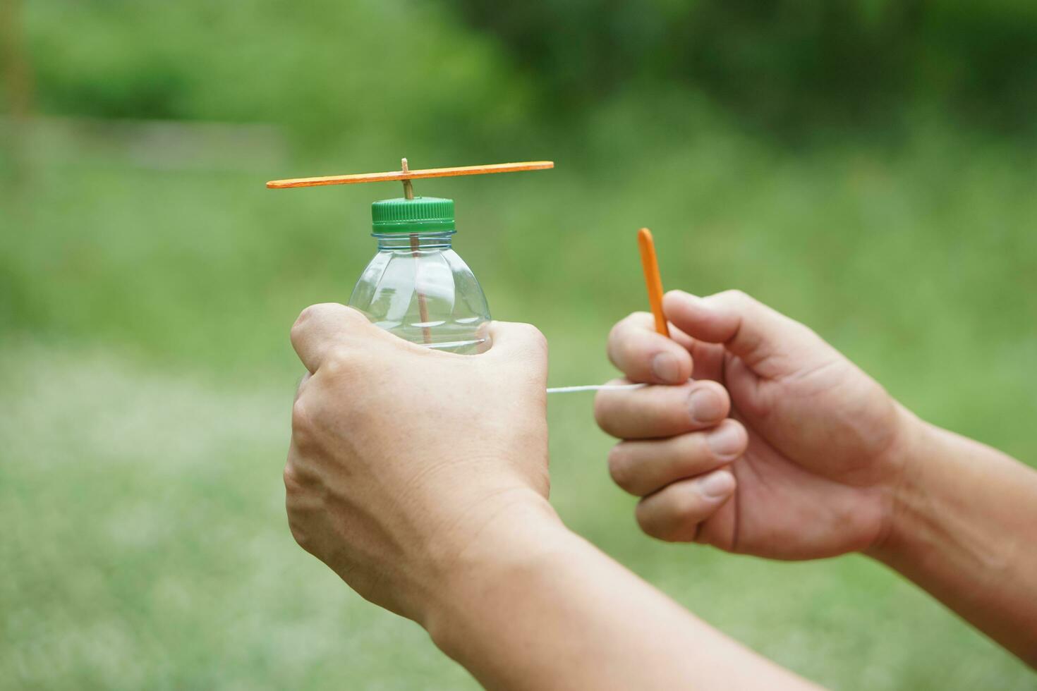 dichtbij omhoog handen houden diy speelgoed- gemaakt van plastic fles, touw en ijs room stok. concept, recycle ambachten. speelgoed- voor kinderen, onderwijs hulp, pret werkzaamheid voor actief aan het leren. spinnen voor beweging. diy helikopter foto