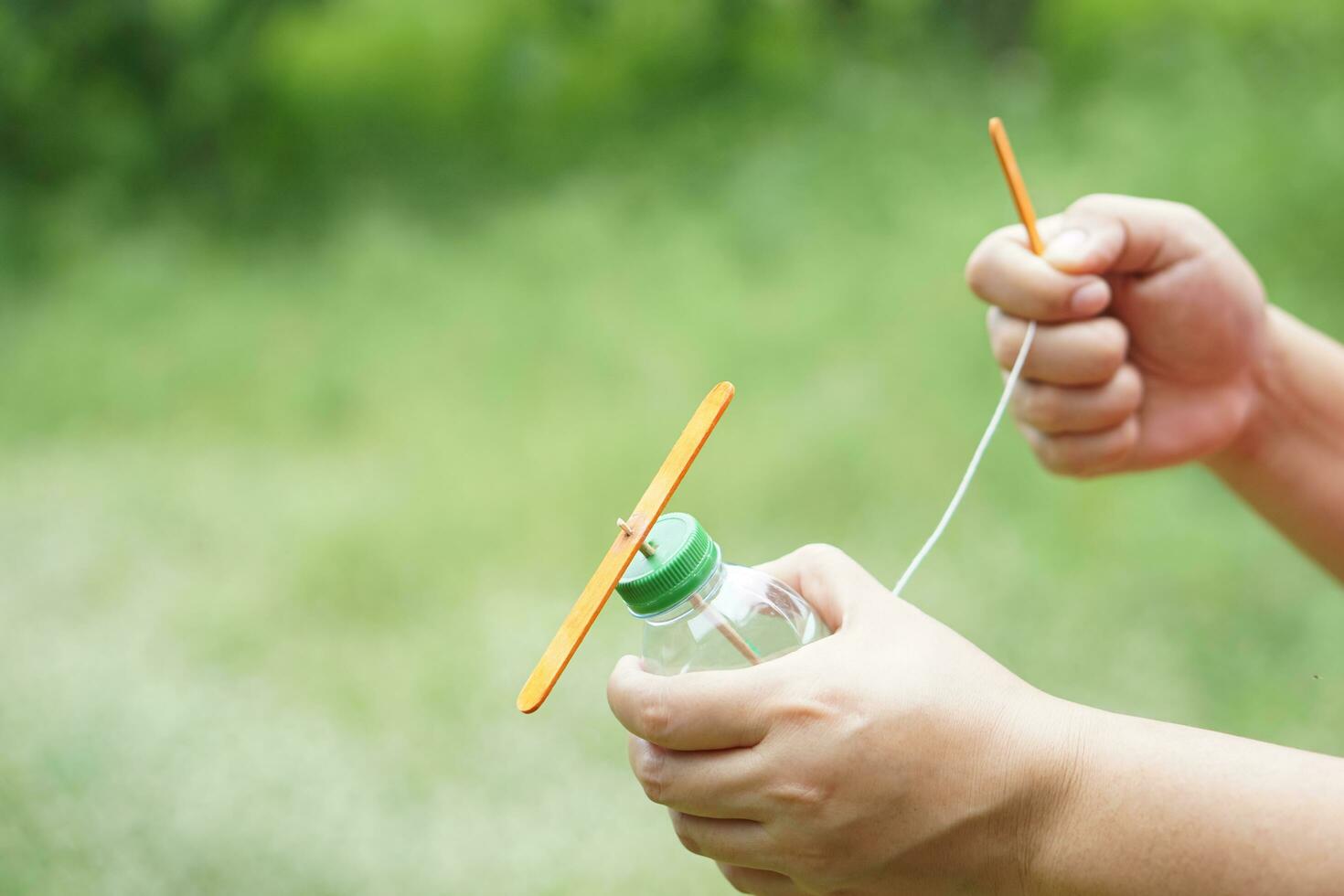 dichtbij omhoog handen houden diy speelgoed- gemaakt van plastic fles, touw en ijs room stok. concept, recycle ambachten. speelgoed- voor kinderen, onderwijs hulp, pret werkzaamheid voor actief aan het leren. spinnen voor beweging. diy helikopter foto