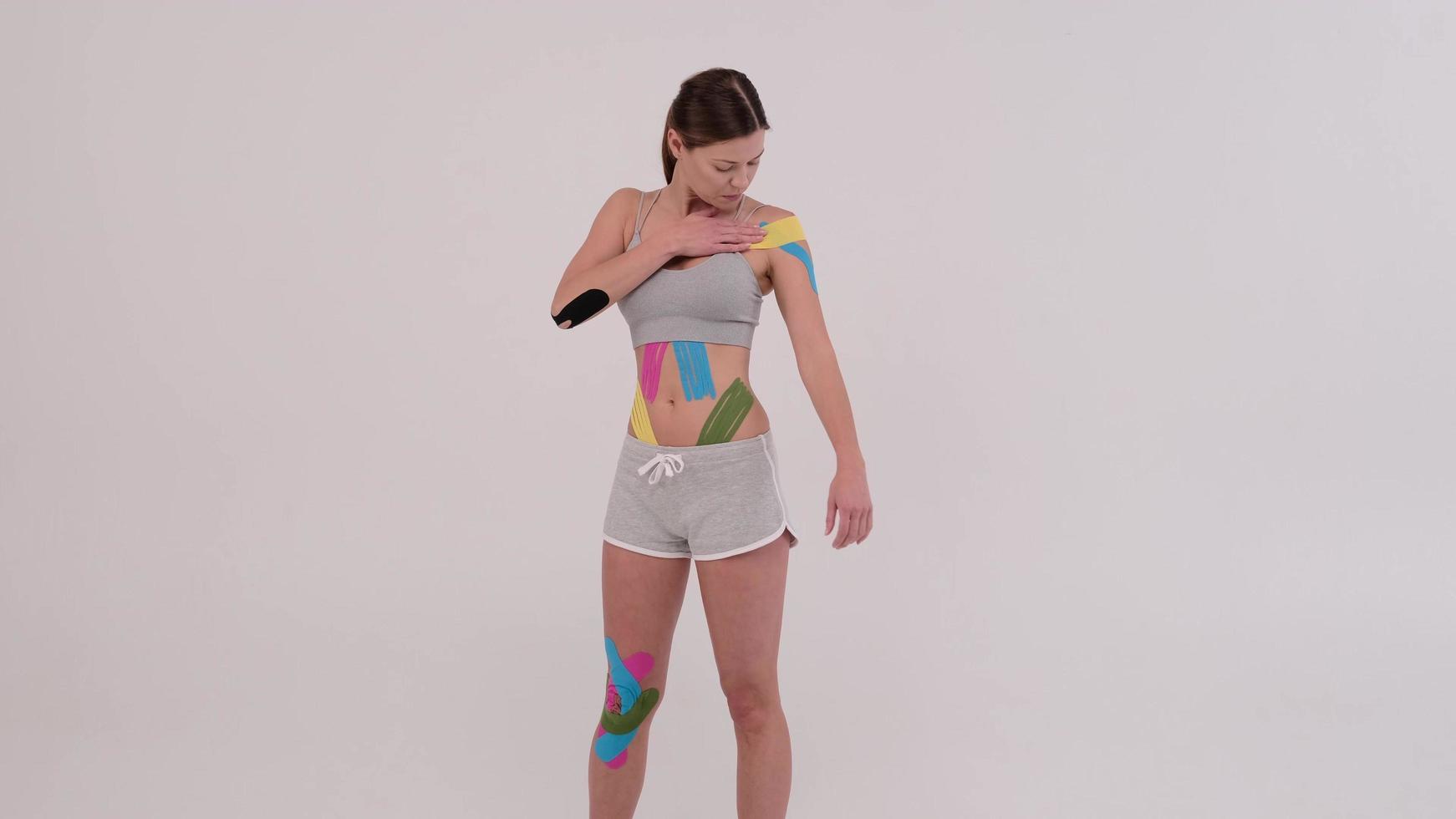 mooie jonge vrouwelijke atleet die kleurrijke kinesiotape op haar lichaam stelt foto