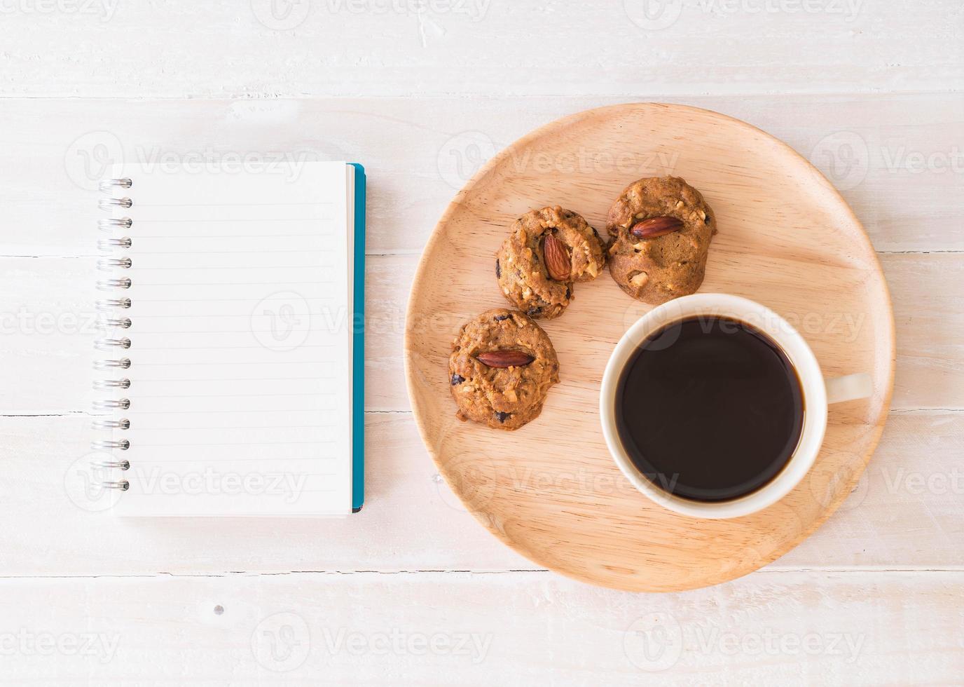 zwarte koffie en koekjes met notitieboekje op tafel foto