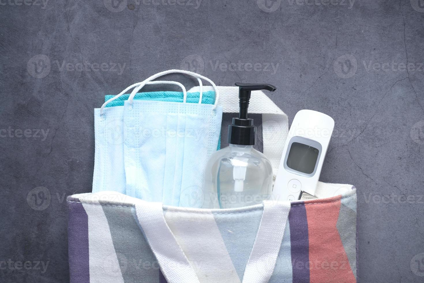 chirurgische maskers, thermometer en handdesinfecterend middel op zwarte achtergrond foto