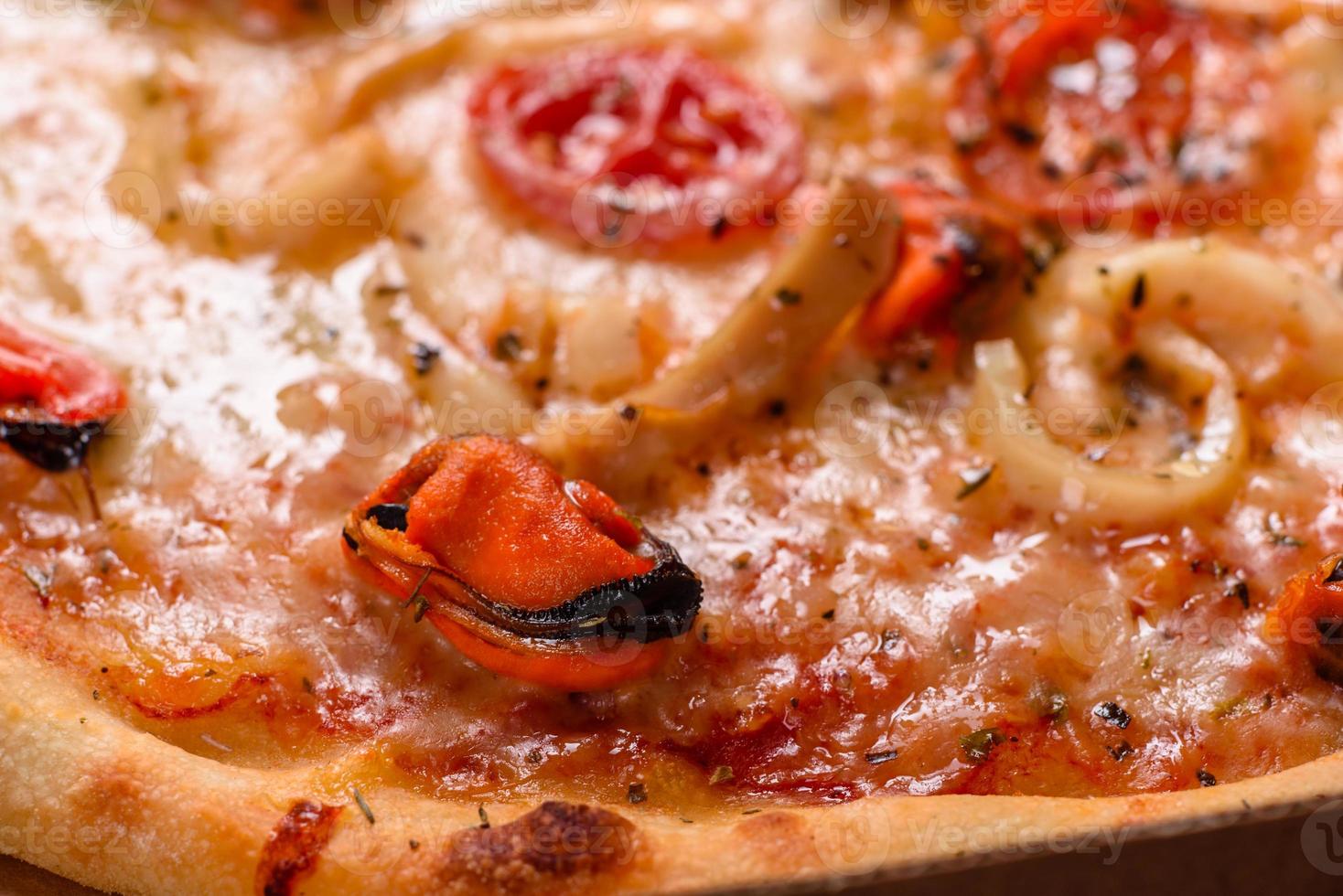 smakelijke gesneden pizza met zeevruchten en tomaat op een betonnen ondergrond foto