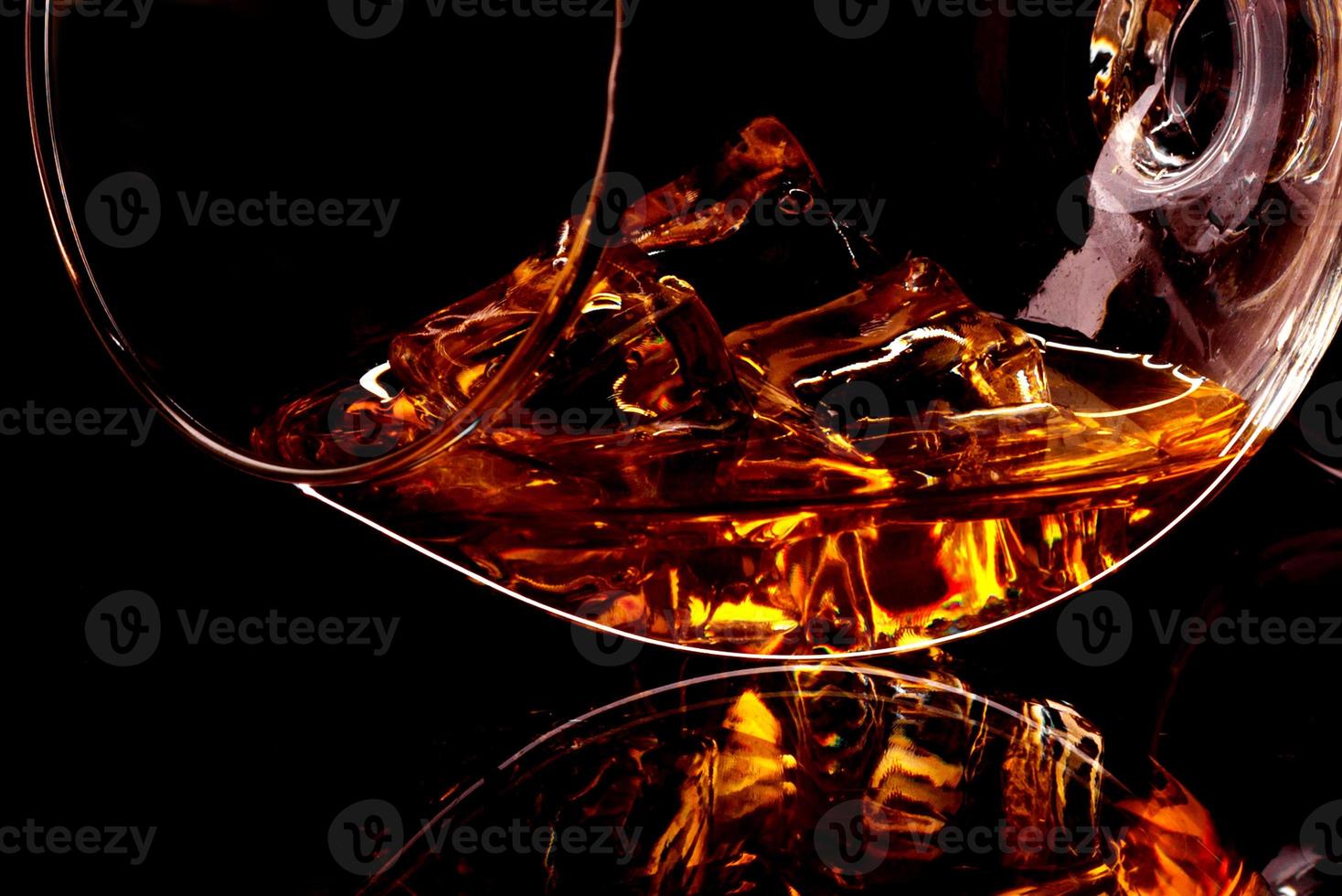 whisky met ijs in glas geïsoleerd op zwarte achtergrond foto