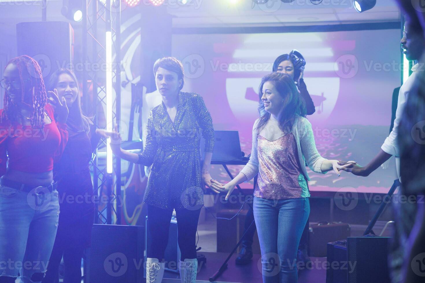 jong clubbezoekers vriendinnetjes Holding handen en dansen samen in nachtclub. Dames vieren en feesten met vrienden Aan dansvloer terwijl ontspannende Bij discotheek in druk club foto