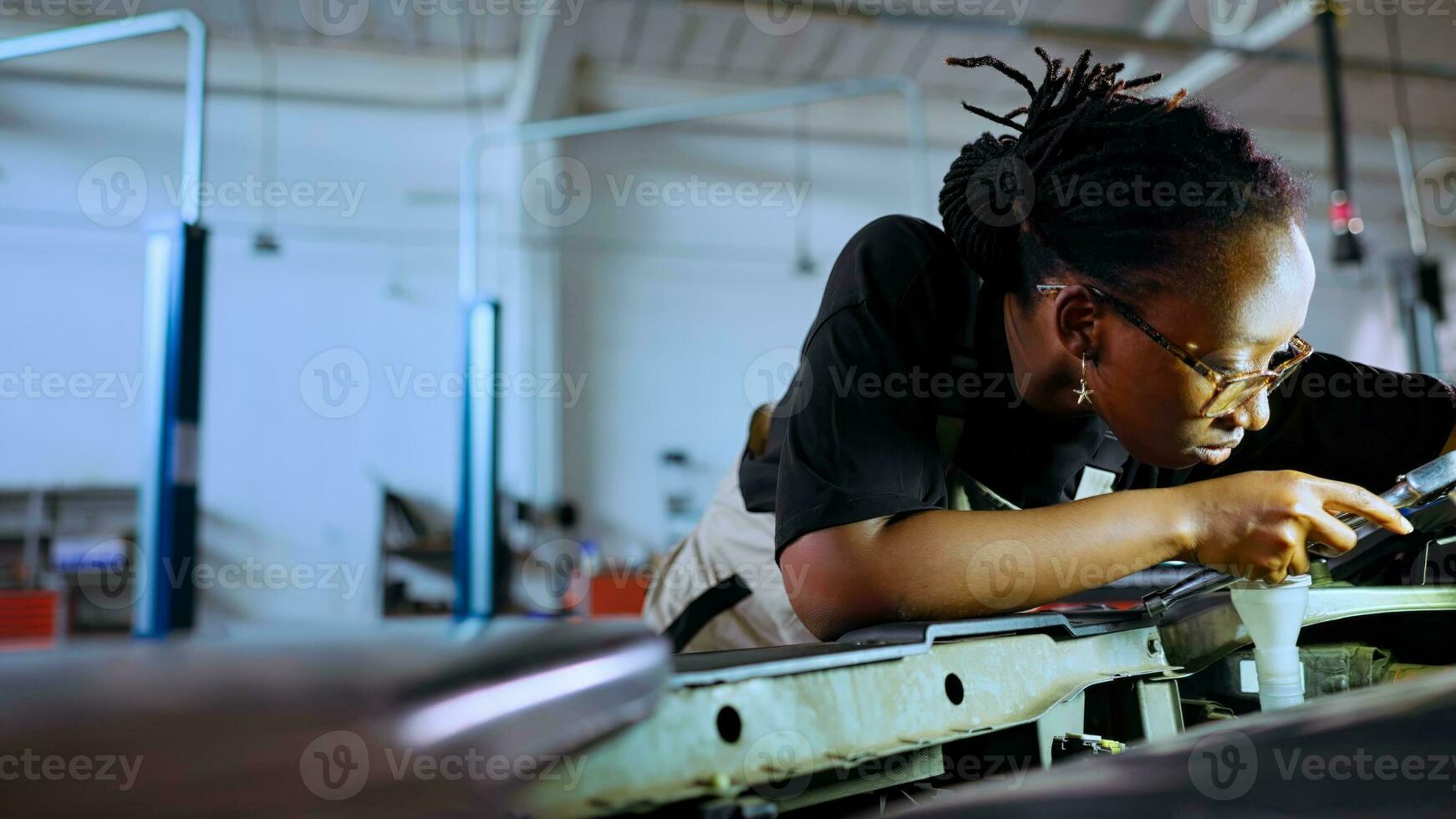 pov schot van gekwalificeerd klusjesman opening auto kap in reparatie winkel, gebruik makend van werk licht naar controleren voor schade gedurende onderhoud. bipoc garage deskundige gebruik makend van professioneel gereedschap naar kijken binnen voertuig foto