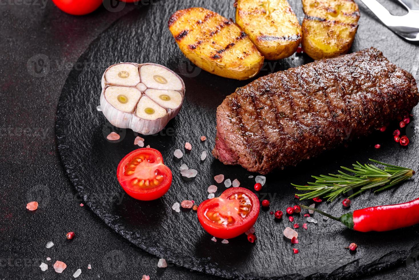 ribeye steak met aardappelen, uien en cherrytomaatjes foto