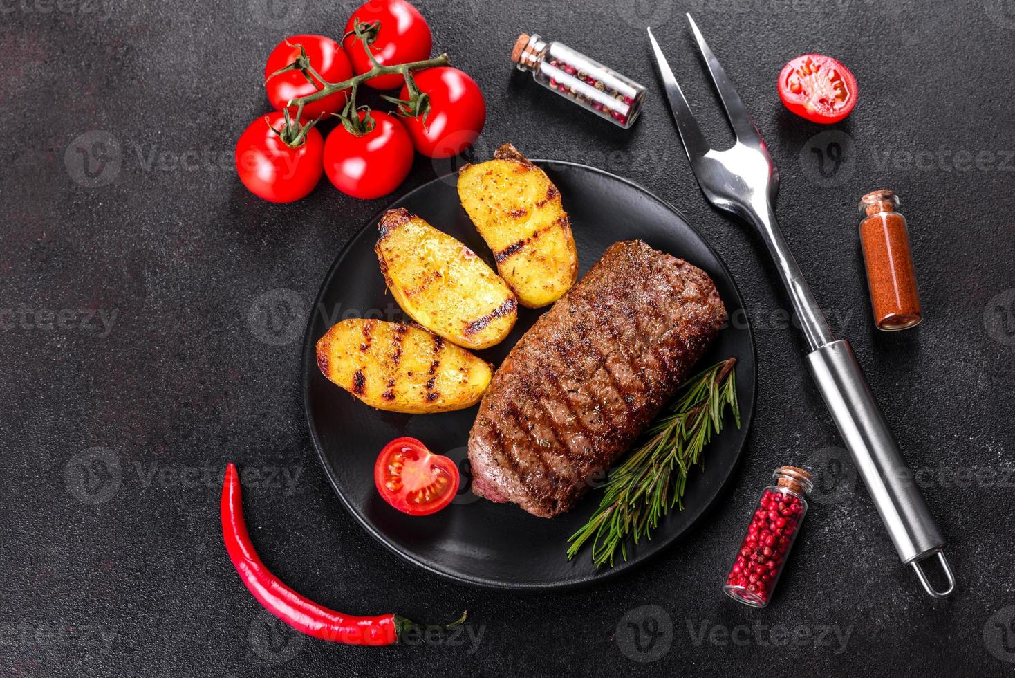 ribeye steak met aardappelen, uien en cherrytomaatjes foto