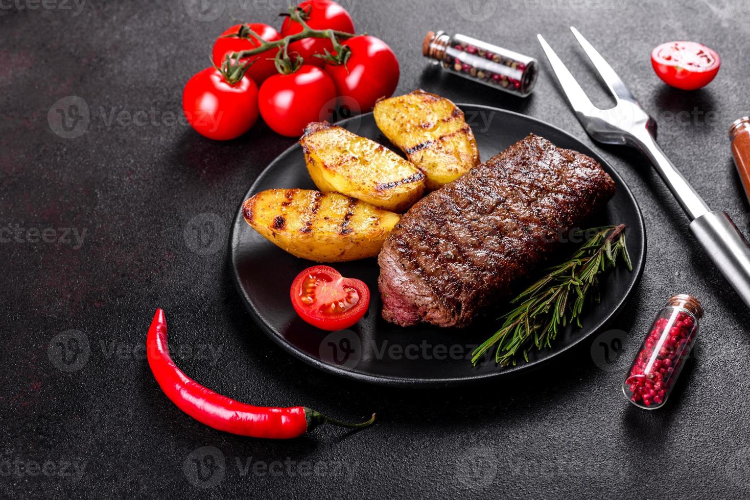 ribeye steak met aardappelen, uien en cherrytomaatjes foto