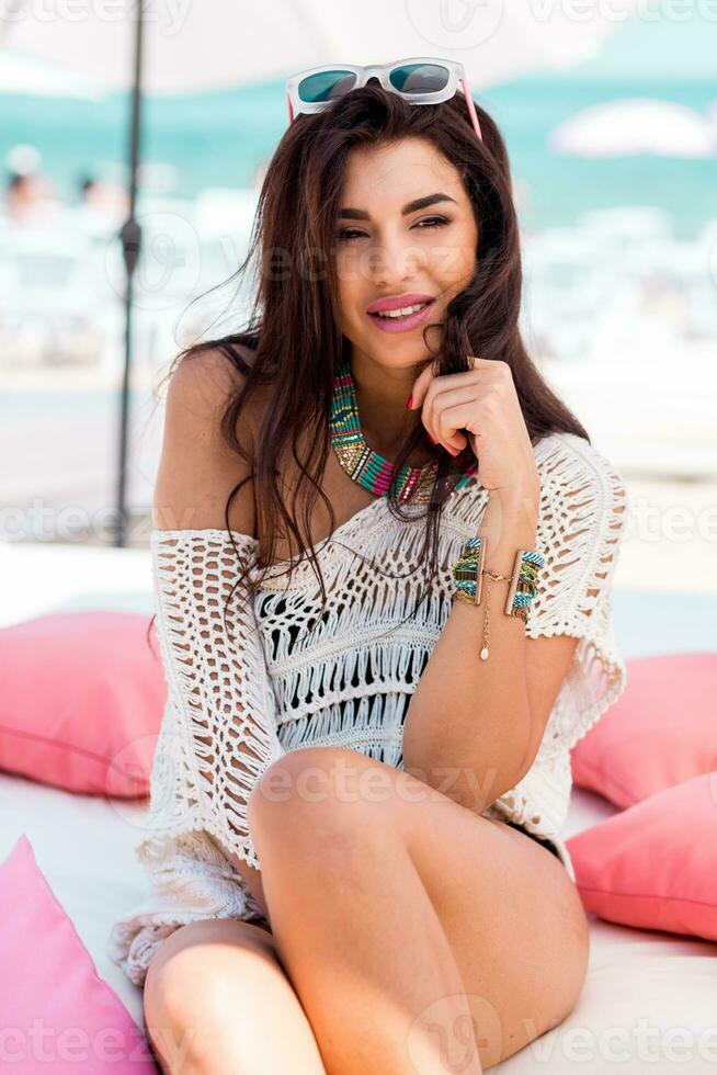 zomer portret van mooi brunette vrouw chillen in de strand club. tropisch accessoires. foto