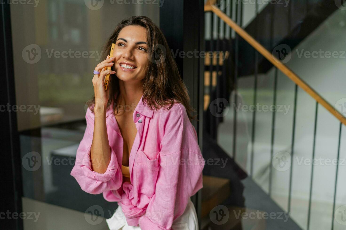 succesvol vrouw in roze blouse pratend door mobiel telefoon en lachend. foto