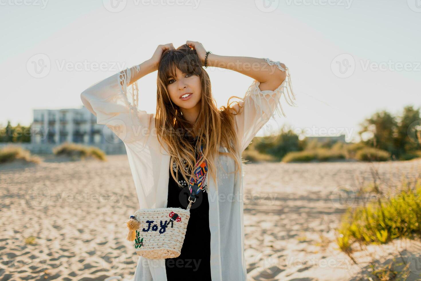 romantisch meisje met lang haar- wandelen Aan de strand. Boheems stijl, rietje zak helder maken omhoog. foto