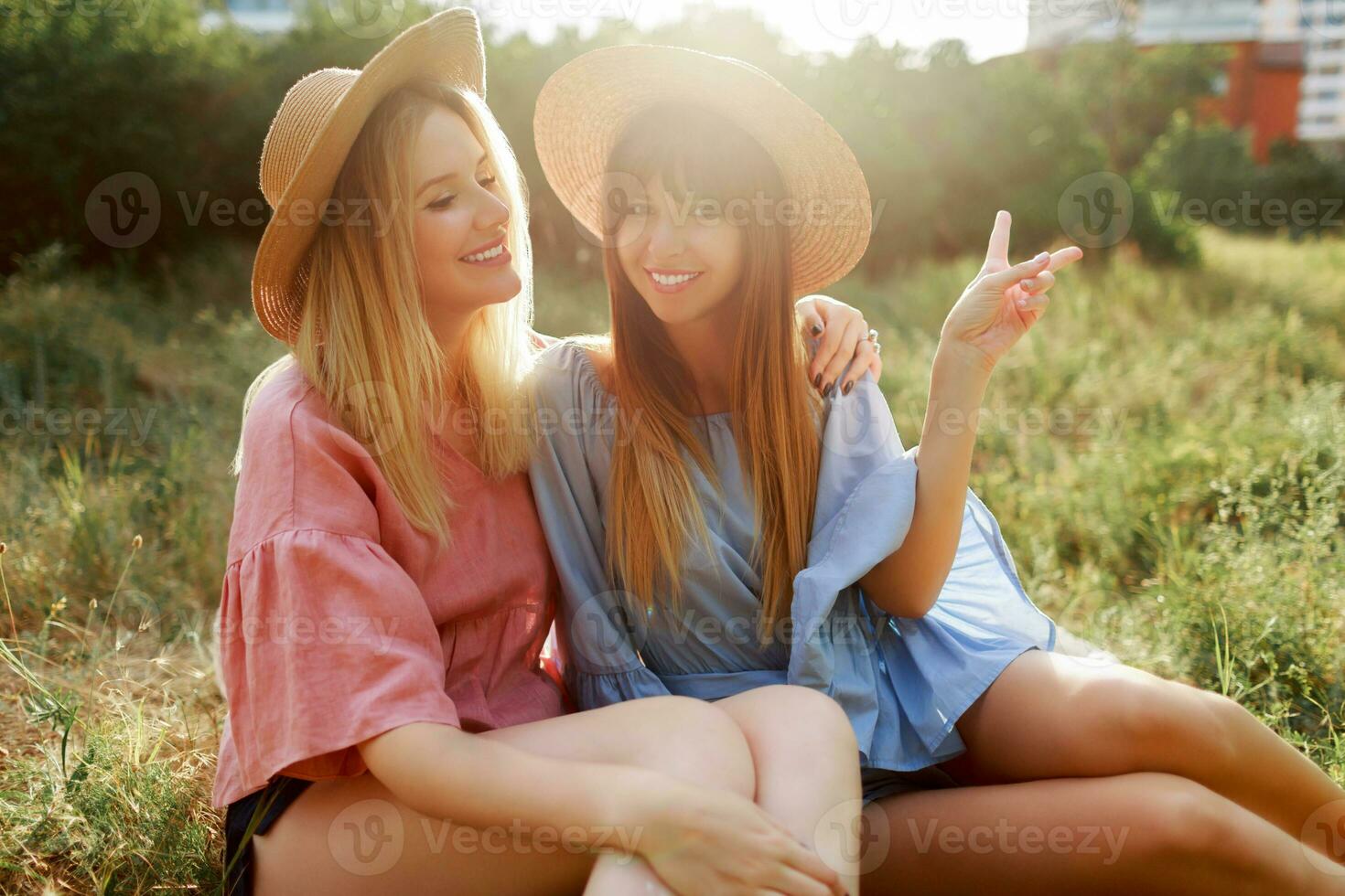 twee mooi Dames in rietje hoed uitgeven vakantie in platteland, drinken sprankelend wijn. foto