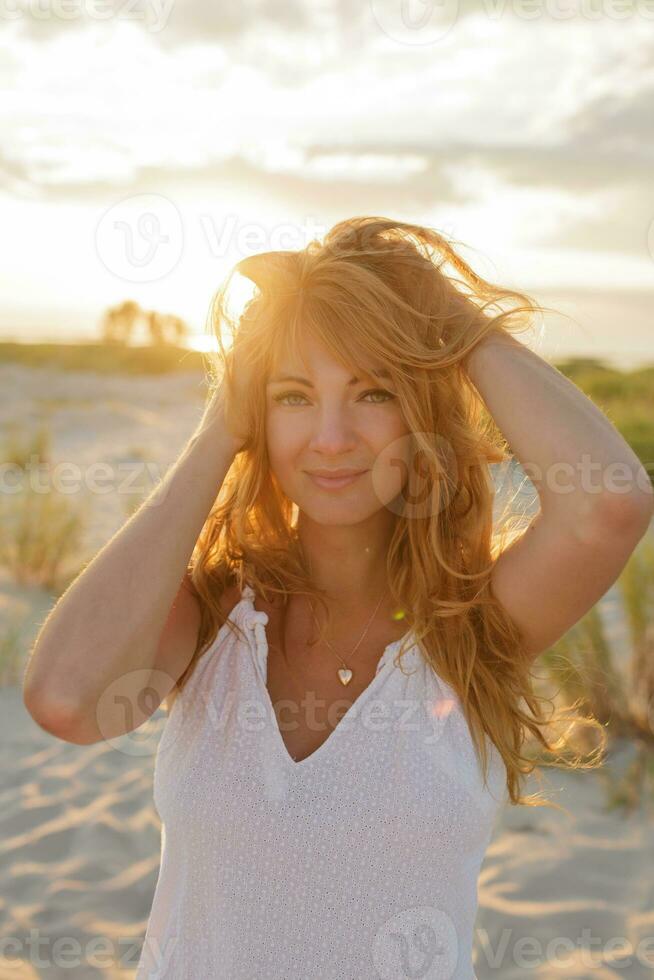 bevallig gember vrouw genieten verbazingwekkend zonsondergang Aan de strand. boho stijl. foto