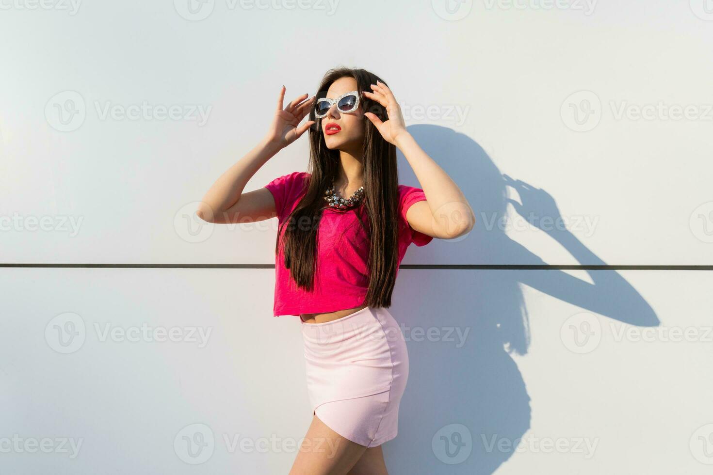 modieus brunette vrouw in zomer kleren en zonnebril poseren over- wit stedelijk achtergrond. foto